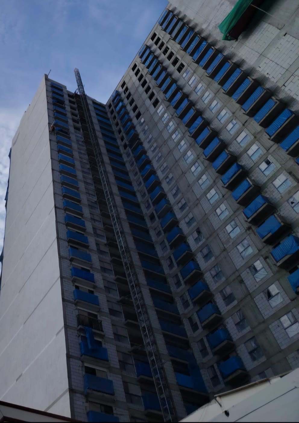 Fachada de torre en proceso de tarrajeo con andamio colgante
